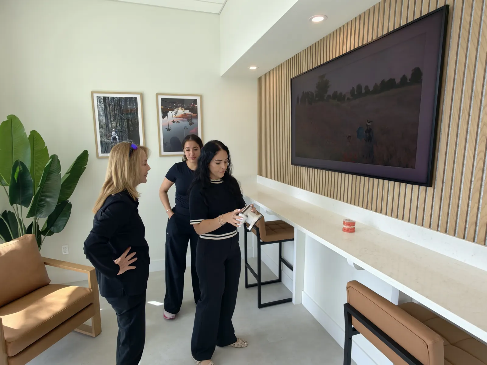 The consultation lounge at Rubin Orthodontics, with an oak slat wall, framed artwork and leather bar stools
