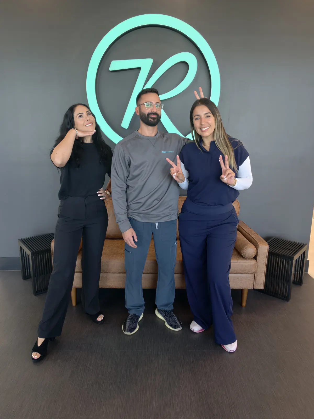 The Rubin Orthodontics team laughing and making peace signs in reception